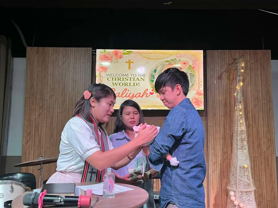 A pastor praying over a baby at a child dedication