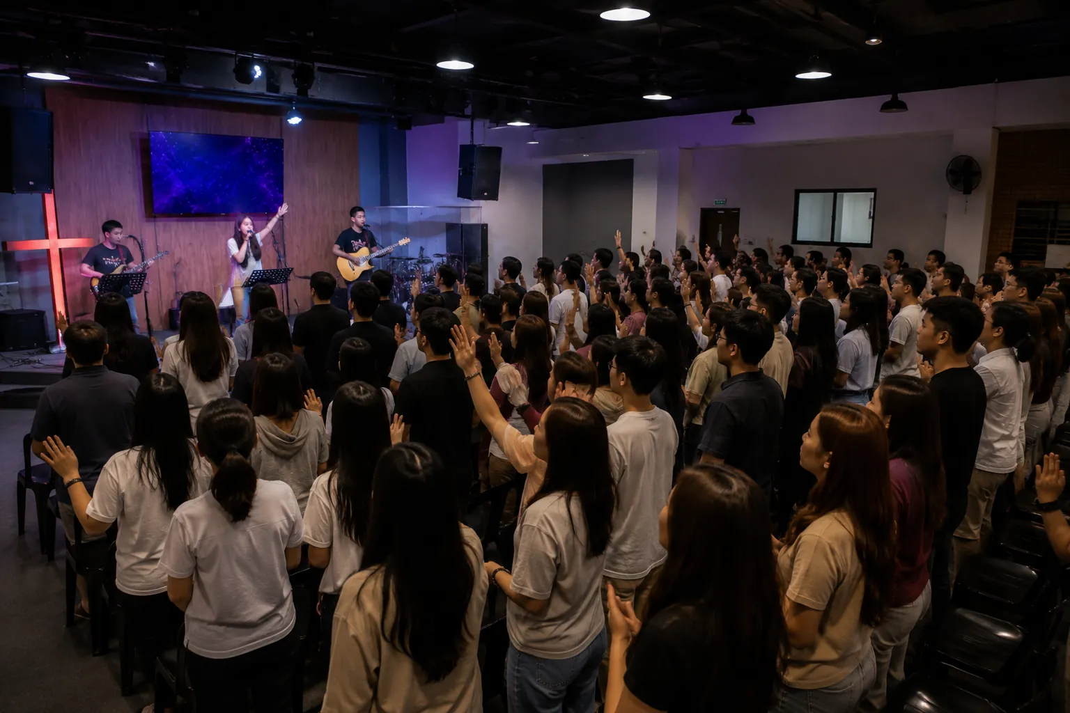 The congregation standing in worship with hands raised, the band on the platform